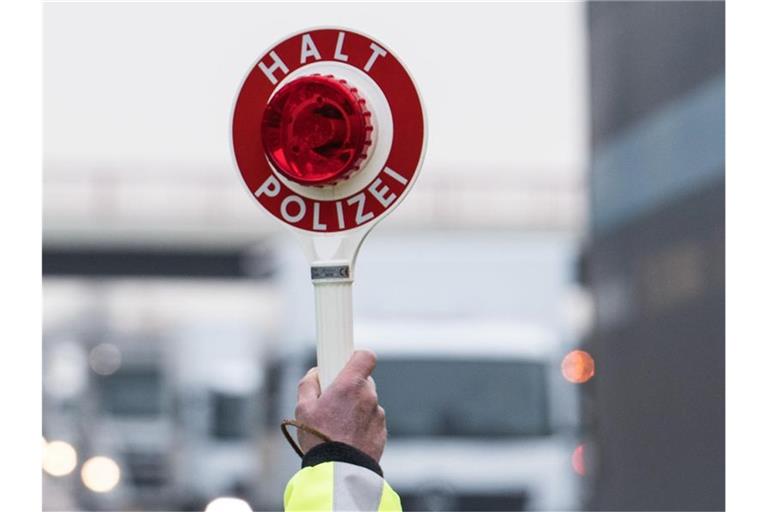 Ein Polizeibeamter hält eine Polizeikelle hoch. Foto: Soeren Stache/dpa/Archivbild