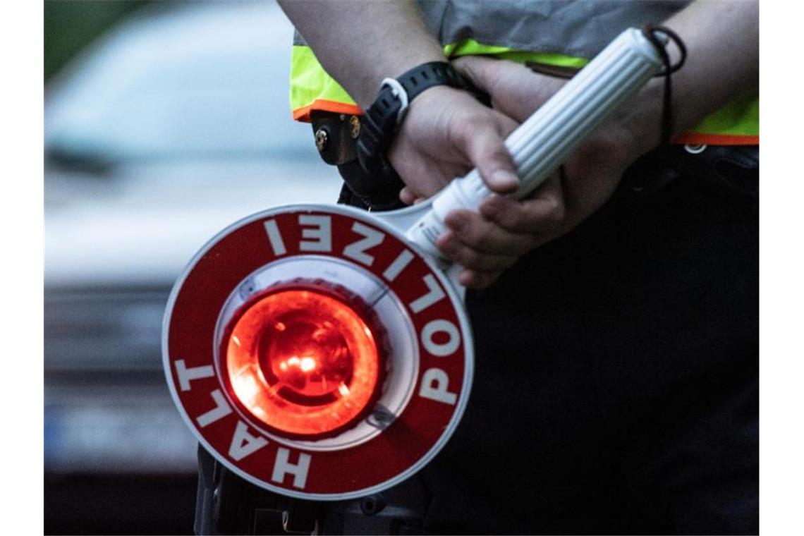 Ein Polizist hält an einer Kontrollstelle eine Winkerkelle in der Hand. Foto: Paul Zinken/dpa/ZB/Symbolbild