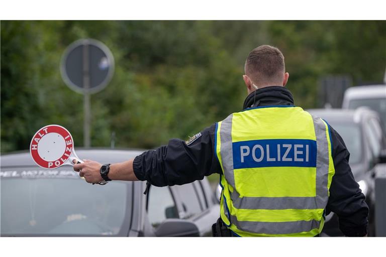 Ein Polizist hält Fahrzeuge an der Grenze zu Deutschland an.