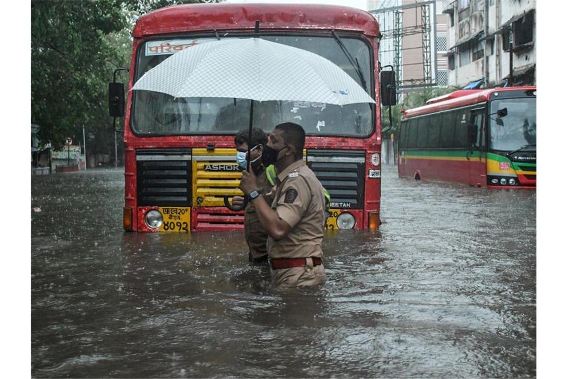 Indische Marine: Lastkahn sinkt bei Zyklon Ein Polizist hilft in Mumbai einem Fahrer eines öffentlichen Verkehrsmittels, eine überschwemmte Straße zu überqueren. Foto: Ashish Vaishnav/SOPA Images via ZUMA Wire/dpa