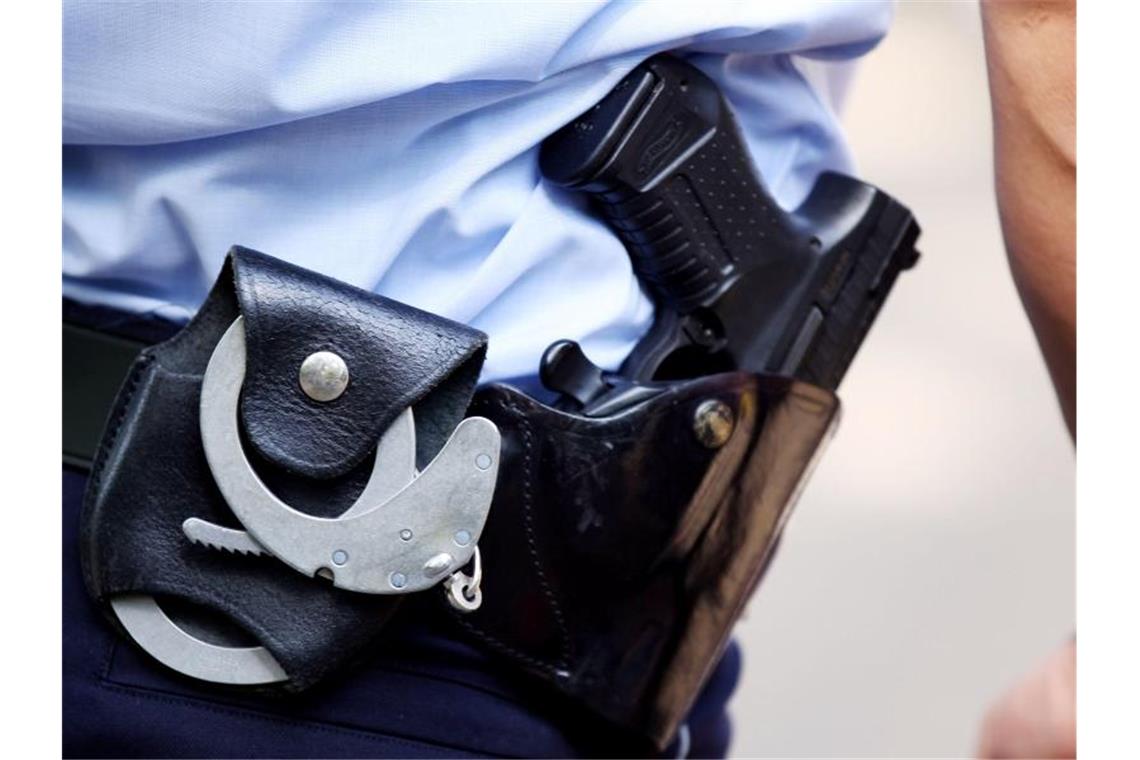 Diebstähle aus Fahrradkörben: Verdächtiger festgenommen Ein Polizist mit Handschellen und Pistole am Gürtel. Foto: Oliver Berg/dpa/Symbolbild/Archivbild