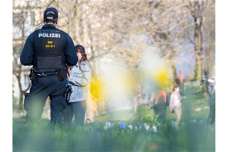 Ein Polizist spricht in einem Park eine Frau an. Foto: Sebastian Gollnow/dpa/Archivbild