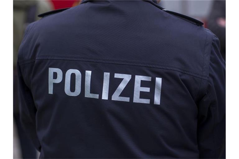 Ein Polizist steht vor einem Polizeifahrzeug. Foto: Jens Büttner/dpa-Zentralbild/ZB/Archiv