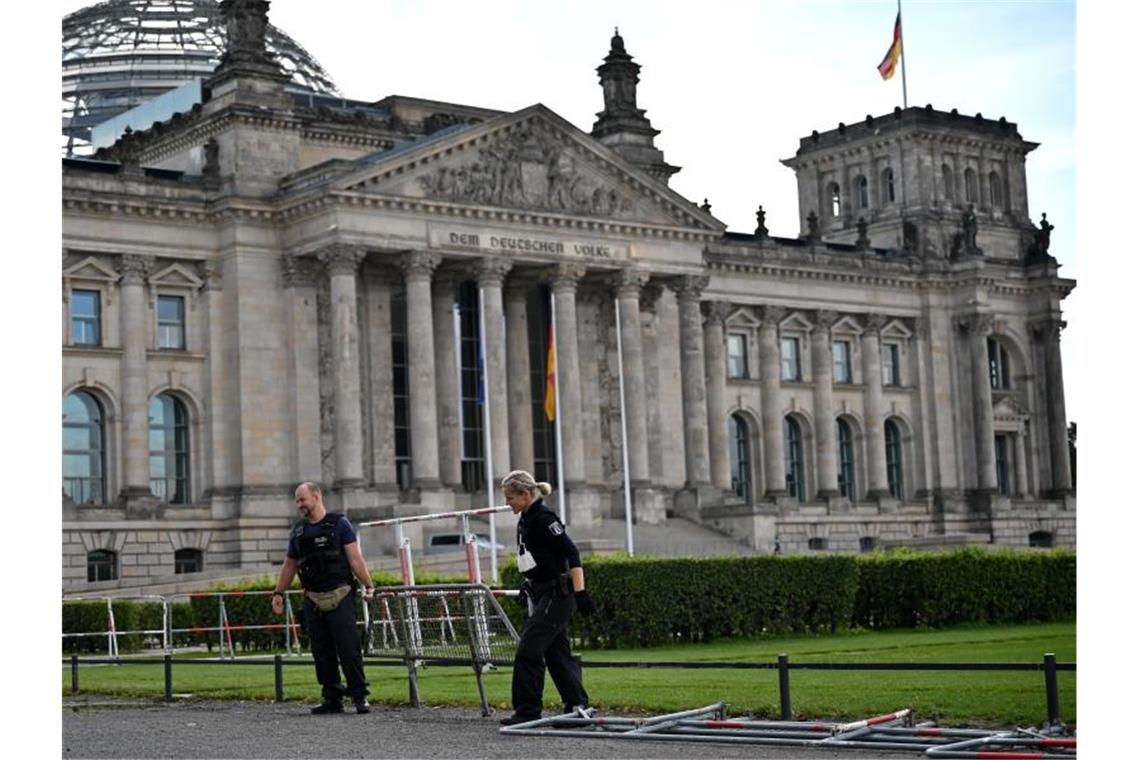 Bundespräsident dankt am Bundestag eingesetzen Polizisten Ein Polizist und eine Polizistin tragen eine Absperrung am Reichstagsgebäude weg. Foto: Johannes Neudecker/dpa