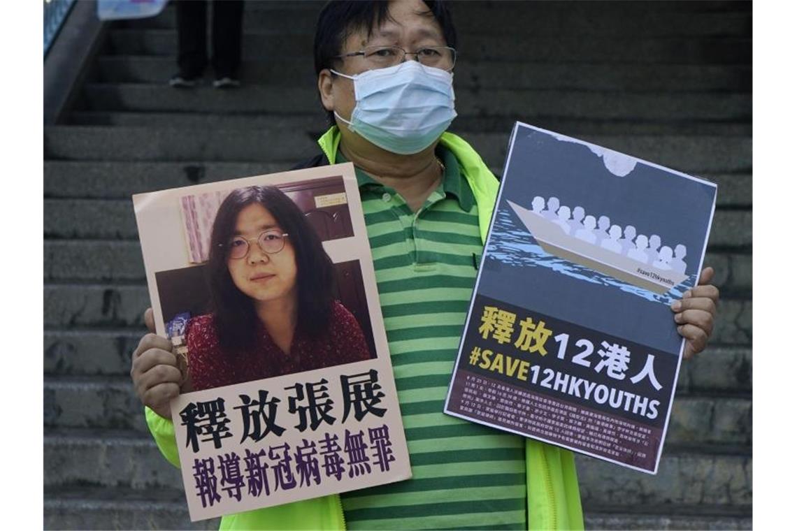 Aus Wuhan berichtet: Chinesin muss für vier Jahre in Haft Ein pro-demokratischer Aktivist zeigt zwei Plakate vor dem Verbindungsbüro der chinesischen Zentralregierung. Auf einem Plakat ist ein Foto der chinesischen Journalistin Zhang Zhan zu sehen. Foto: Kin Cheung/AP/dpa