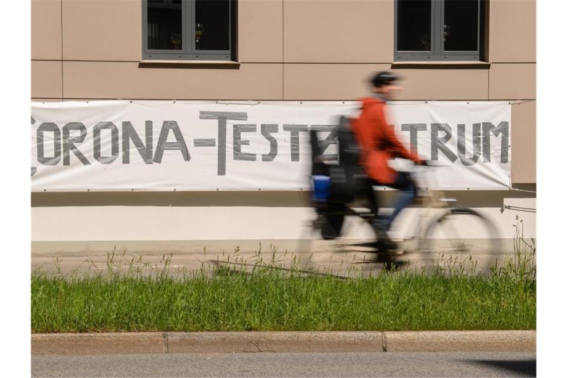 Ein Radfahrer fährt an einem Banner mit der Aufschrift "Corona-Testzentrum" vorbei. Foto: Robert Michael/dpa-Zentralbild/dpa/Symbolbild