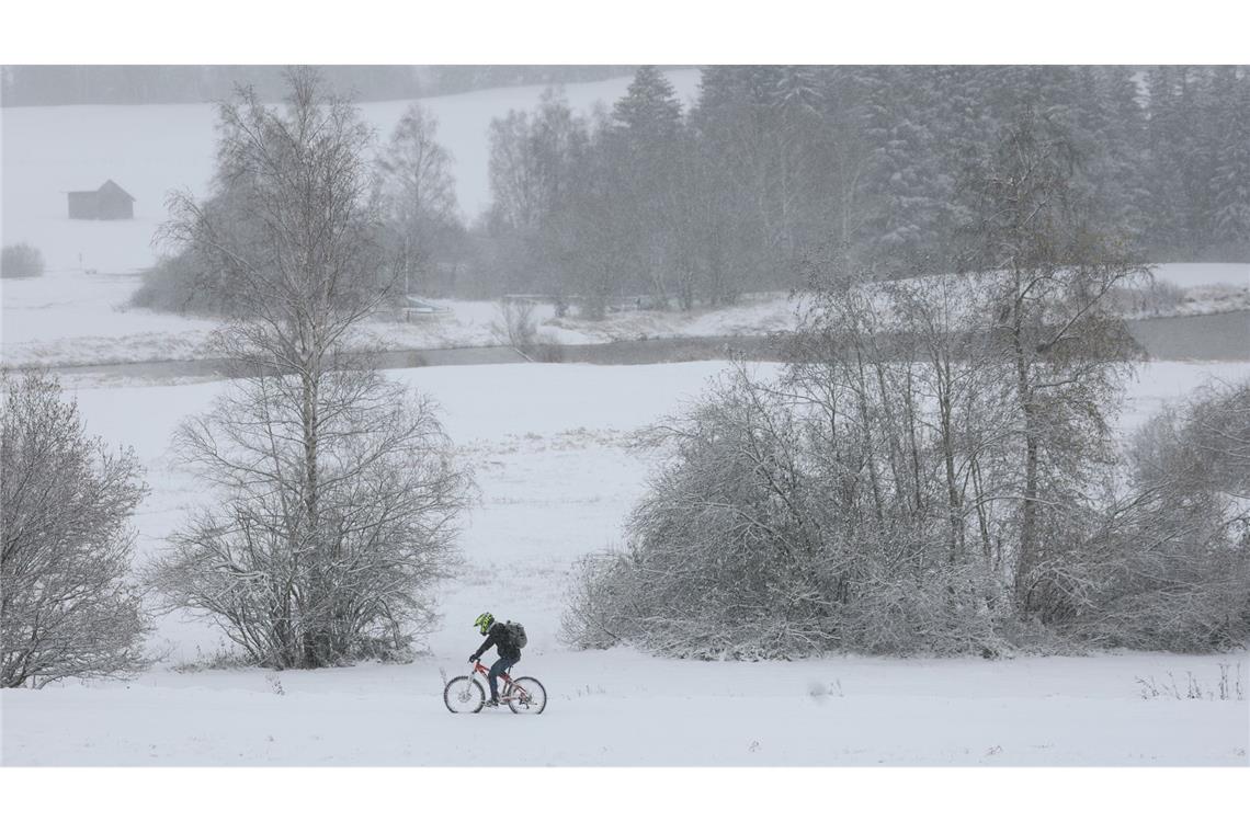 Ein Radfahrer fährt durch die schneebedeckte Landschaft in Bayern.