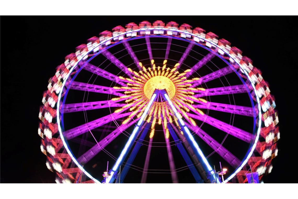 Ein Riesenrad leuchtet bunt auf der Wiesn.