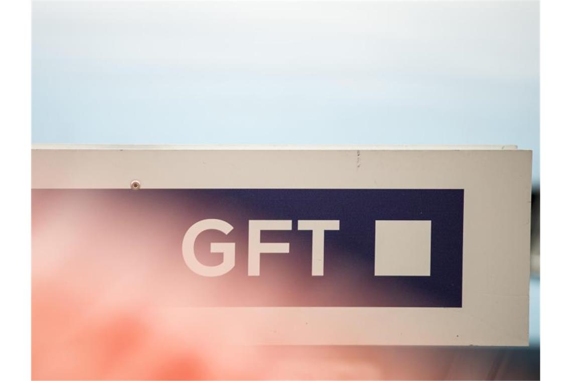 Ein rotes Autos steht auf einem Parkplatz vor einem Schild mit dem Logo des IT-Dienstleisters GFT in Stuttgart. Foto: picture alliance / Sebastian Gollnow/dpa