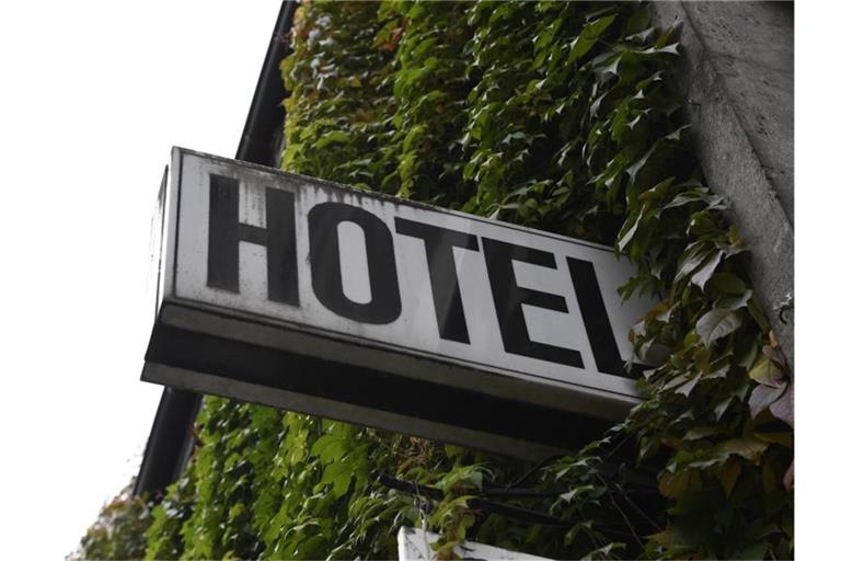 Ein Schild "Hotel" ist an der mit Efeu bewachsenden Wand eines Gebäudes angebracht. Foto: Roberto Pfeil/dpa/Illustration