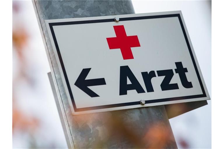 Ein Schild mit der Aufschrift „Arzt“ hängt an einer Straßenlaterne. Foto: Tom Weller/dpa/Symbolbild