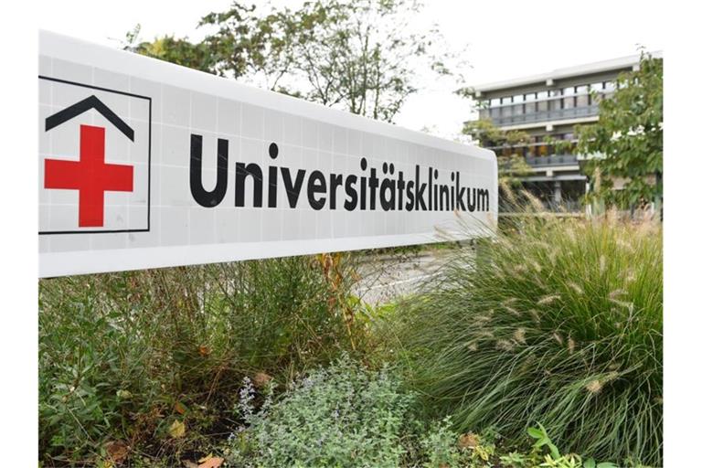 Ein Schild mit der Aufschrift „Universitätsklinikum“ steht an einer Einfahrt zum Universitätsklinikum. Foto: Uwe Anspach/dpa/Archivbild