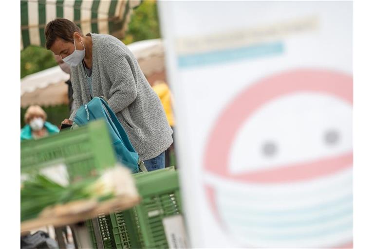 Ein Schild weist auf das Tragen eines Mund-Nasen-Schutzes auf einem Markt hin. Foto: Sebastian Gollnow/dpa