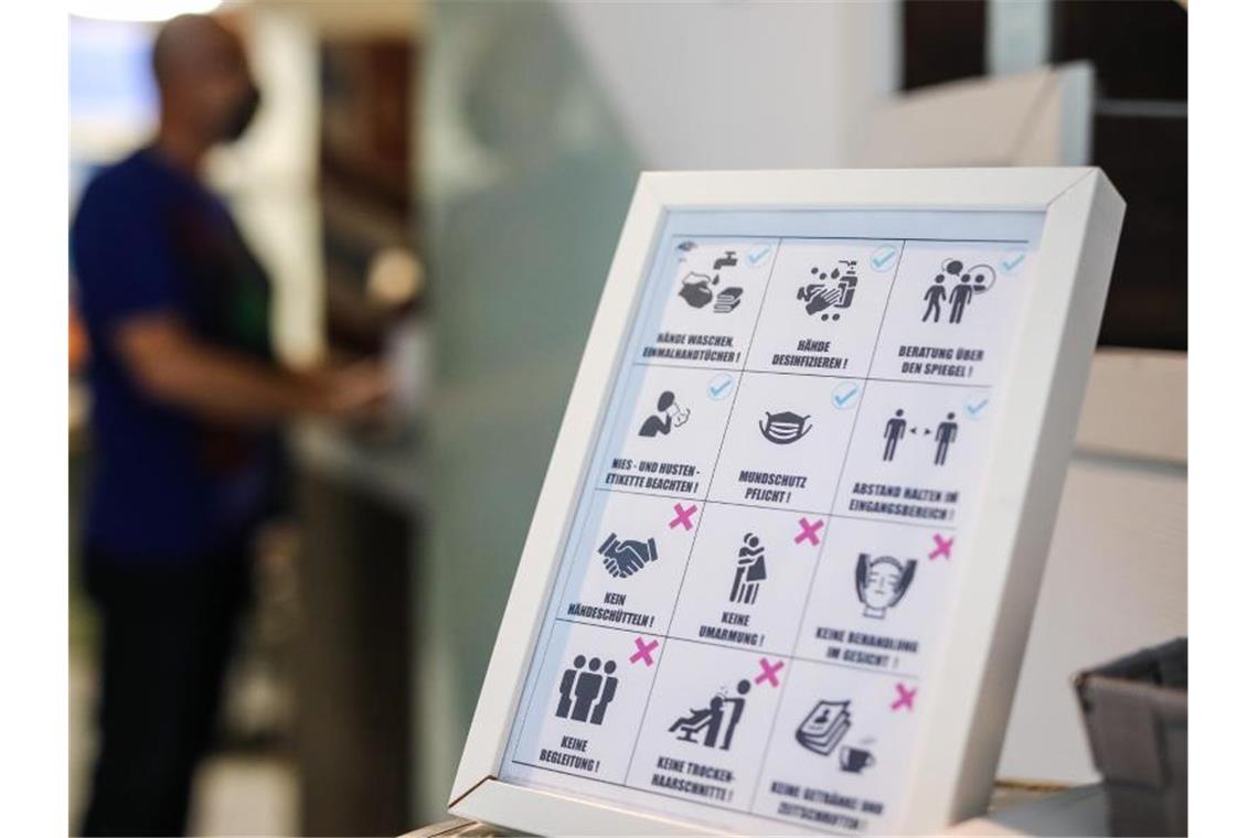 Ein Schild weist in einem Friseursalon auf die neuen Corona-Regeln hin. Foto: Christoph Schmidt/dpa