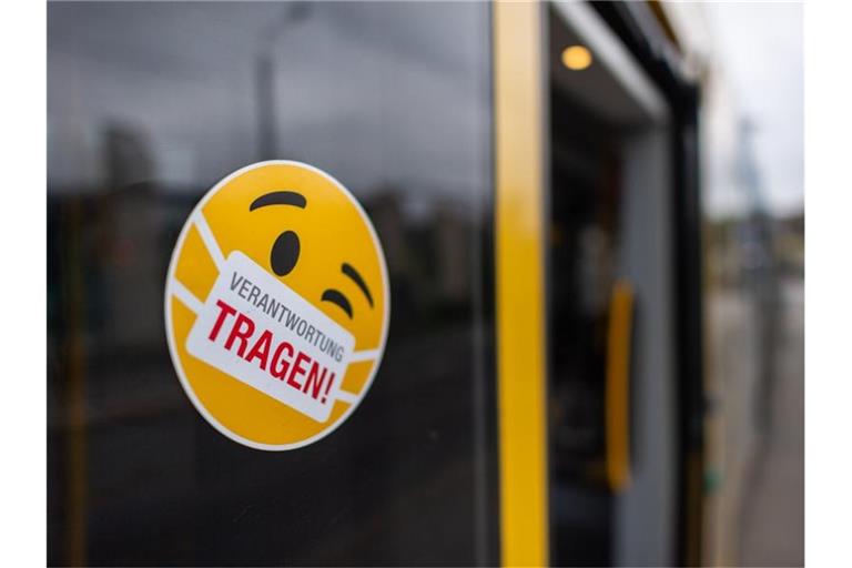 Ein Smiley-Aufkleber mit einem Mundschutz und der Aufschrift "Verantwortung tragen" klebt an einer Scheibe einer Straßenbahn. Foto: Robert Michael/dpa-Zentralbild/dpa/Symbol