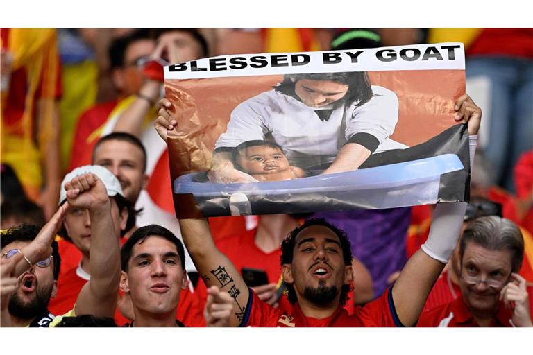 Ein spanischer Fan hält ein Poster von Lionel Messi, der für eine Kampagne das Baby Lamine Yamal badet. Wird es ein Wiedersehen zwischen der Legende und dem spanischen Talent geben?   (Archivfoto).