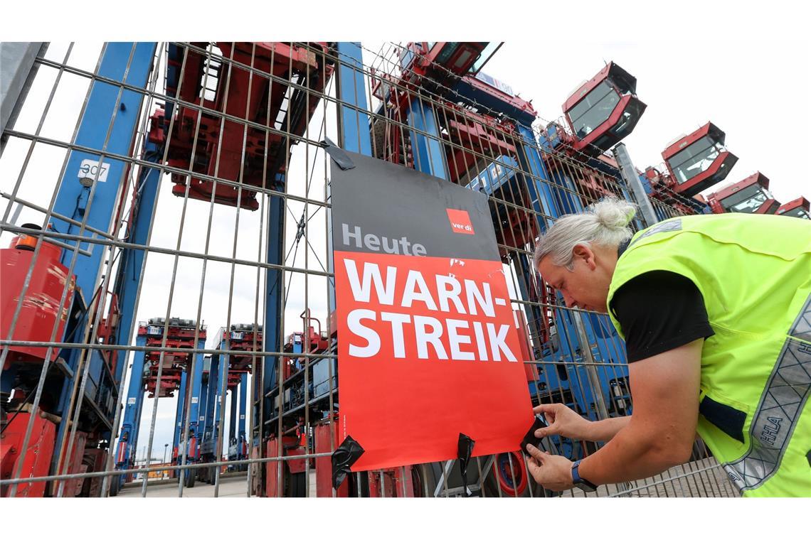 Ein Streikender hängt ein Plakat am Hamburger Hafen auf. (Archivfoto)