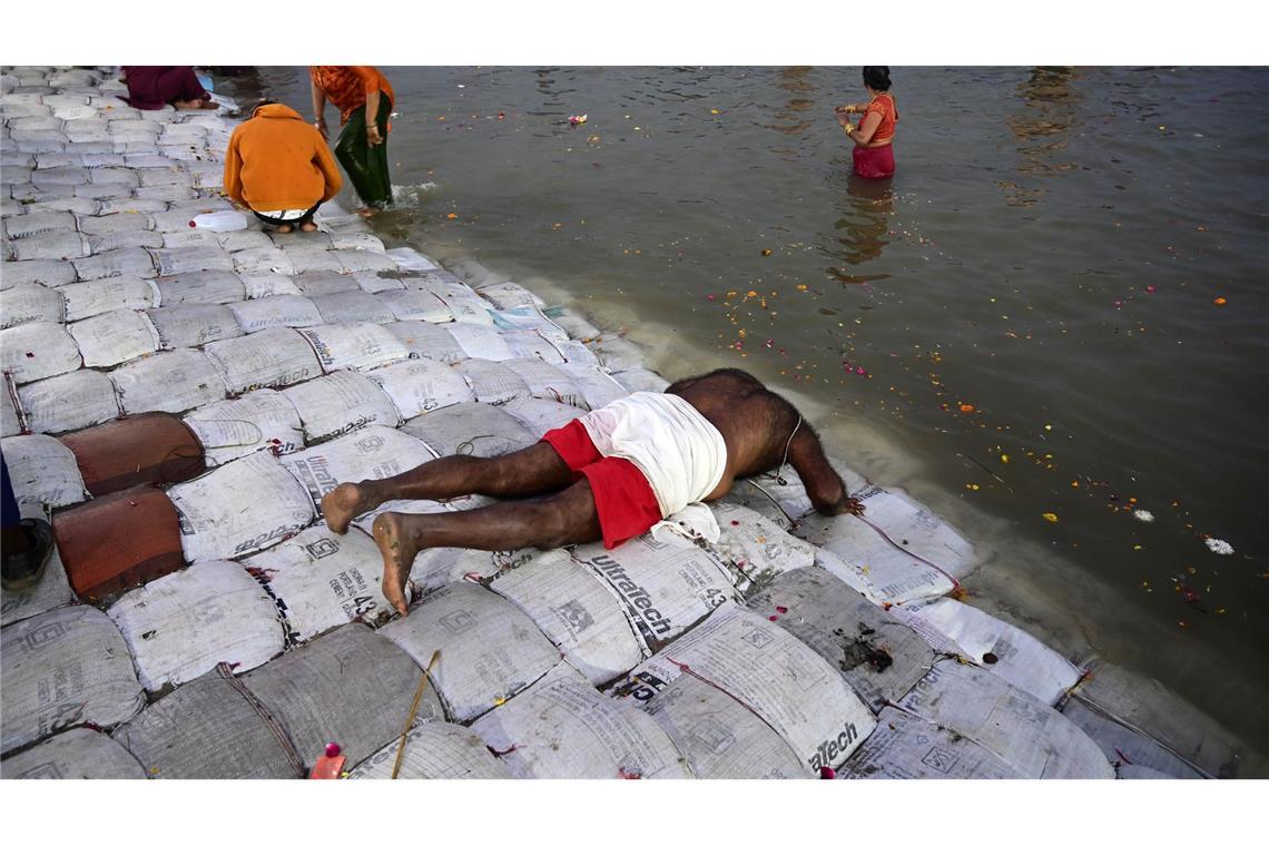 Ein Teilnehmer des Pilgerfests Maha Kumbh Mela spricht ein Gebet, bevor er ein Bad im Fluss nimmt.