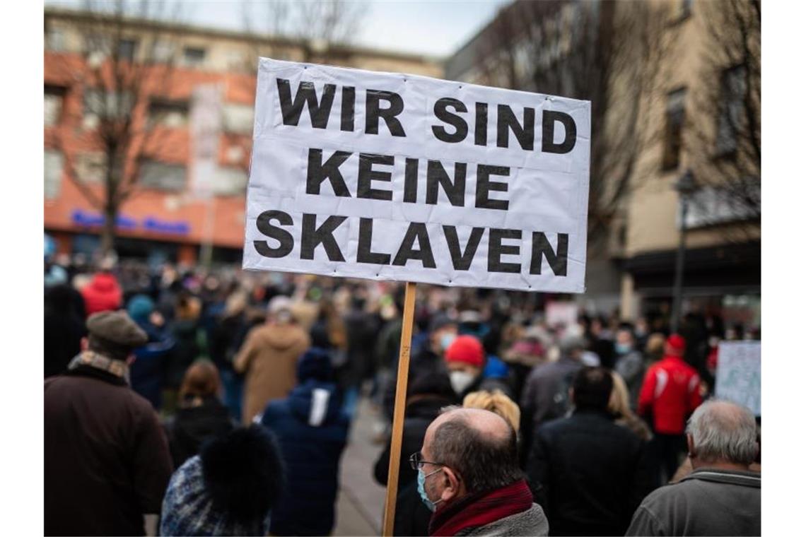 Ein Teilnehmer einer Demonstration gegen die Corona-Maßnahmen hebt ein Transparent in die Höhe. Foto: Christoph Schmidt/dpa/Archivbild