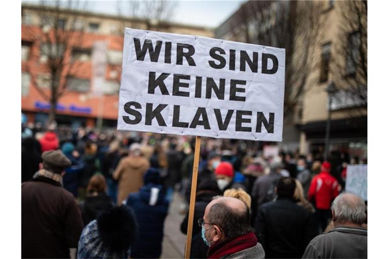 Ein Teilnehmer einer Demonstration gegen die Corona-Maßnahmen hebt ein Transparent in die Höhe. Foto: Christoph Schmidt/dpa/Archivbild