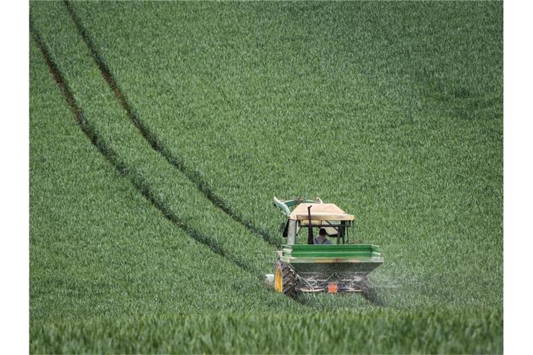 Ein Traktor auf einem ein noch grünen Getreidefeld. Foto: Frank Rumpenhorst/dpa