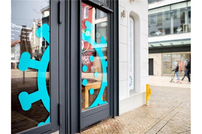 Ein überdimensionales Coronavirus klebt am Fenster eines Cafés in der Oldenburger Innenstadt, das derzeit als Testzentrum genutzt wird. Foto: Hauke-Christian Dittrich/dpa