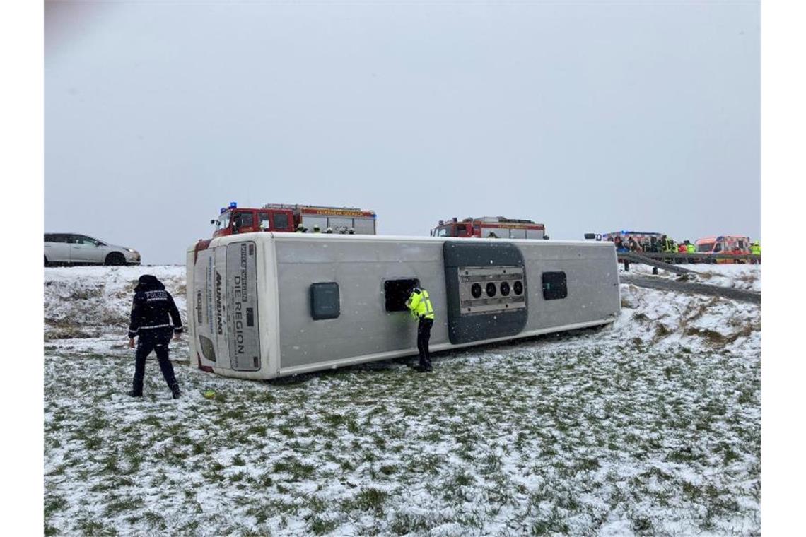 Ein umgekippter Schulbus liegt auf einer Wiese neben der Straße. Foto: Gerd Mägerle/Schwäbische Zeitung/dpa