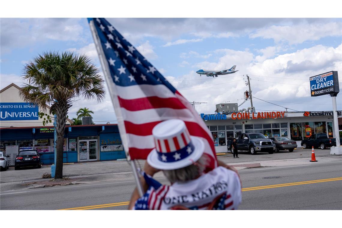 Ein Unterstützer hält eine US-Flagge und beobachtet, wie die Air Force One mit US-Präsident Trump an Bord auf dem Palm Beach International Airport landet.