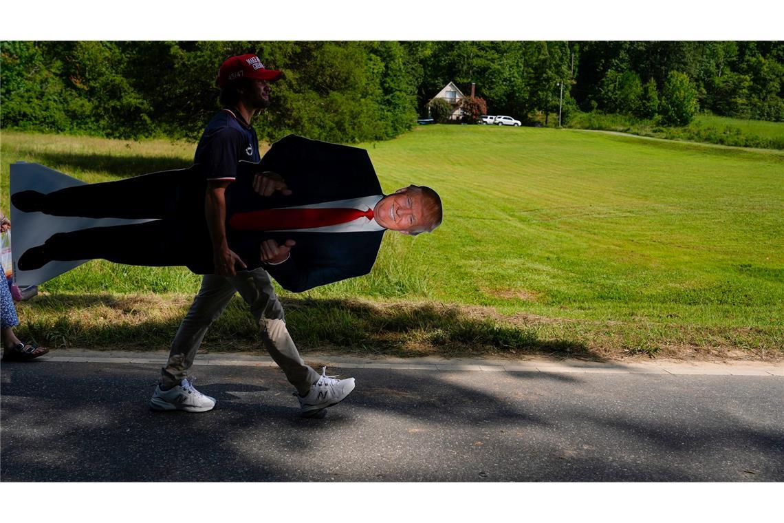 Ein Unterstützer von Donald Trump trägt einen Aufsteller des ehemaligen US-Präsidenten nach einer Wahlkampfveranstaltung in North Carolina.