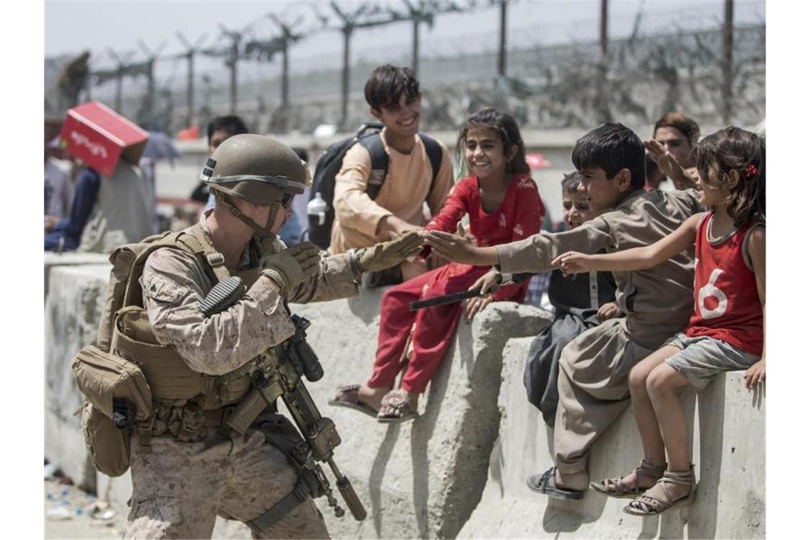Verzweiflung in Kabul - Berichte über Hinrichtungen Ein US-Marine spielt mit Kindern, die während der Evakuierung am Hamid Karzai International Airport warten. Foto: Uncredited/U.S. Marine Corps/AP/dpa