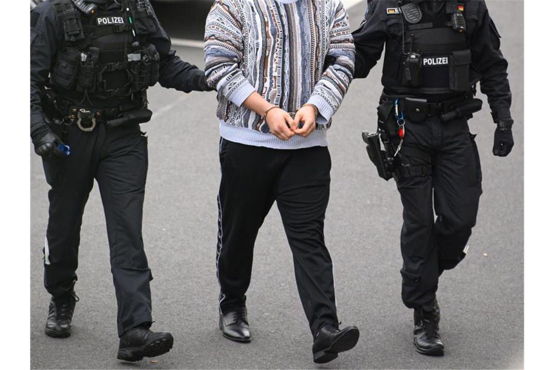 Nach Juwelendiebstahl: Verdächtige aus Clan-Milieu gefasst Ein verdächtiger Mann (M) im Fall um den Kunstdiebstahl im Grünen Gewölbe wird von Polizisten in das Gebäude des Oberlandesgerichts Dresden geführt. Foto: Robert Michael/dpa-Zentralbild/dpa
