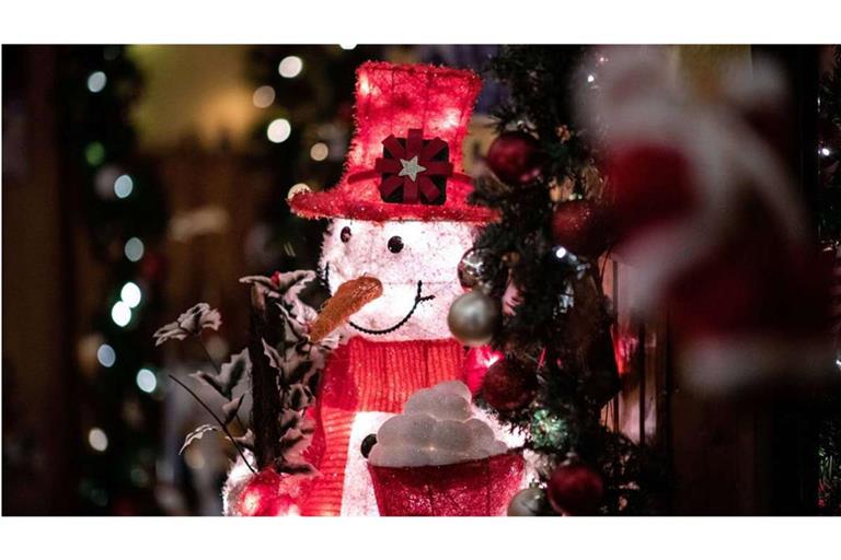 Ein von innen beleuchteter Deko-Schneemann steht im Flur der weihnachtlich dekorierten Wohnung