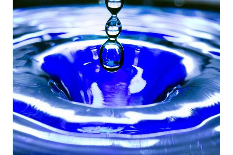 Ein Wassertropfen fällt in eine blaue Wasserschüssel. Foto: Jens Büttner/zb/dpa/Symbolbild