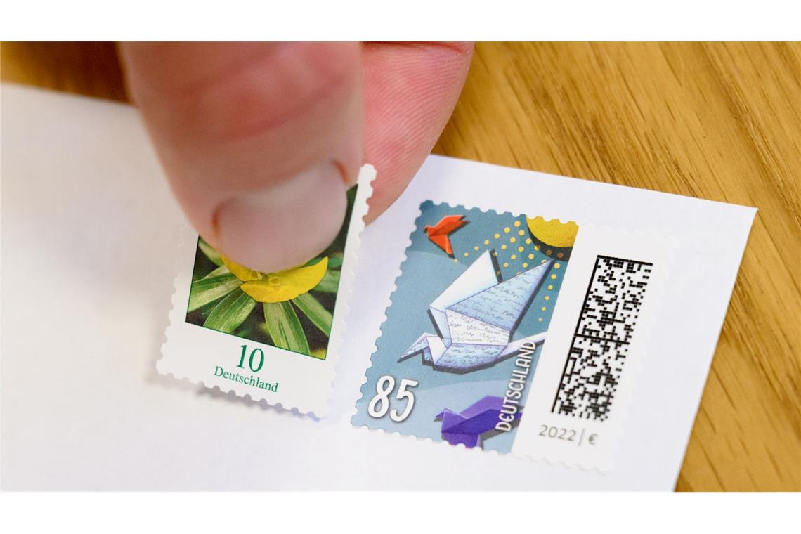 Eine 10-Cent-Briefmarke wird neben eine 85-Cent-Briefmarke geklebt (gestellte Szene).