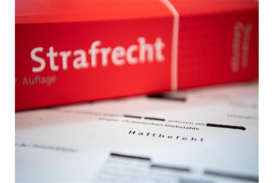 Staatstheater-Mitarbeiter zu Bewährungsstrafe verurteilt Eine Abschrift eines Haftbefehls liegt mit einem Strafrecht-Buch auf dem Tisch. Foto: Tom Weller/dpa/Illustration
