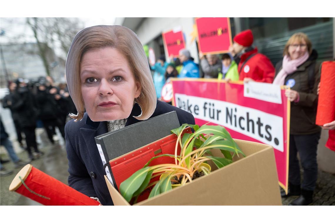 Eine Aktivistin demonstriert mit einer Maske von Bundesinnenministerin Nancy Faeser.