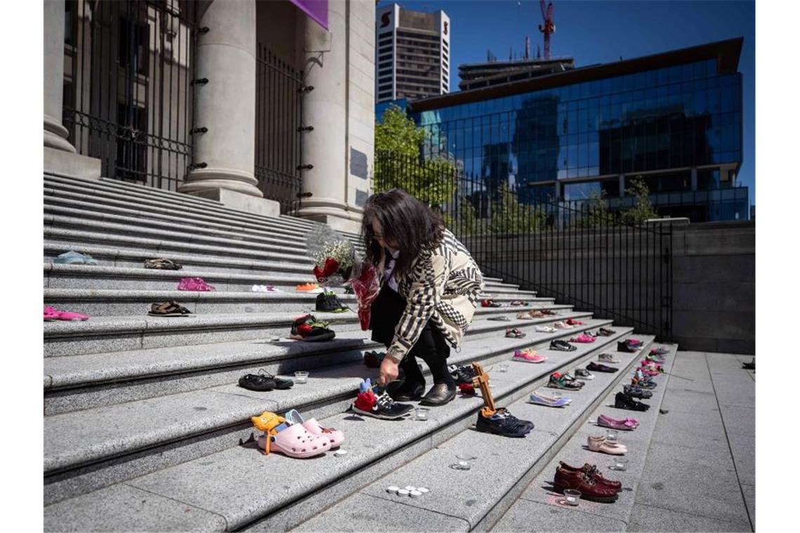 Was geschah mit den kanadischen Ureinwohner-Kindern? Eine Angehörige einer indigenen Volksgruppe legt eine Rose auf eines von 215 Paar Kinderschuhen auf den Stufen der Vancouver Art Gallery. Foto: Darryl Dyck/The Canadian Press via ZUMA/dpa