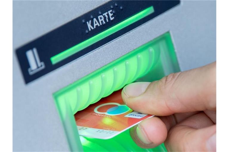 Eine Bankkundin steckt ihre Girokarte in einen Geldautomaten. Foto: Fabian Sommer/dpa/Illustration