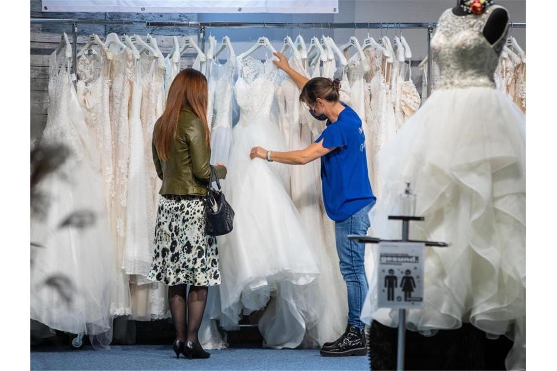 Eine Besucherin der Hochzeitsmesse sieht sich verschiedene Hochzeitskleider am Stand eines Ausstellers an. Foto: Christoph Schmidt/dpa