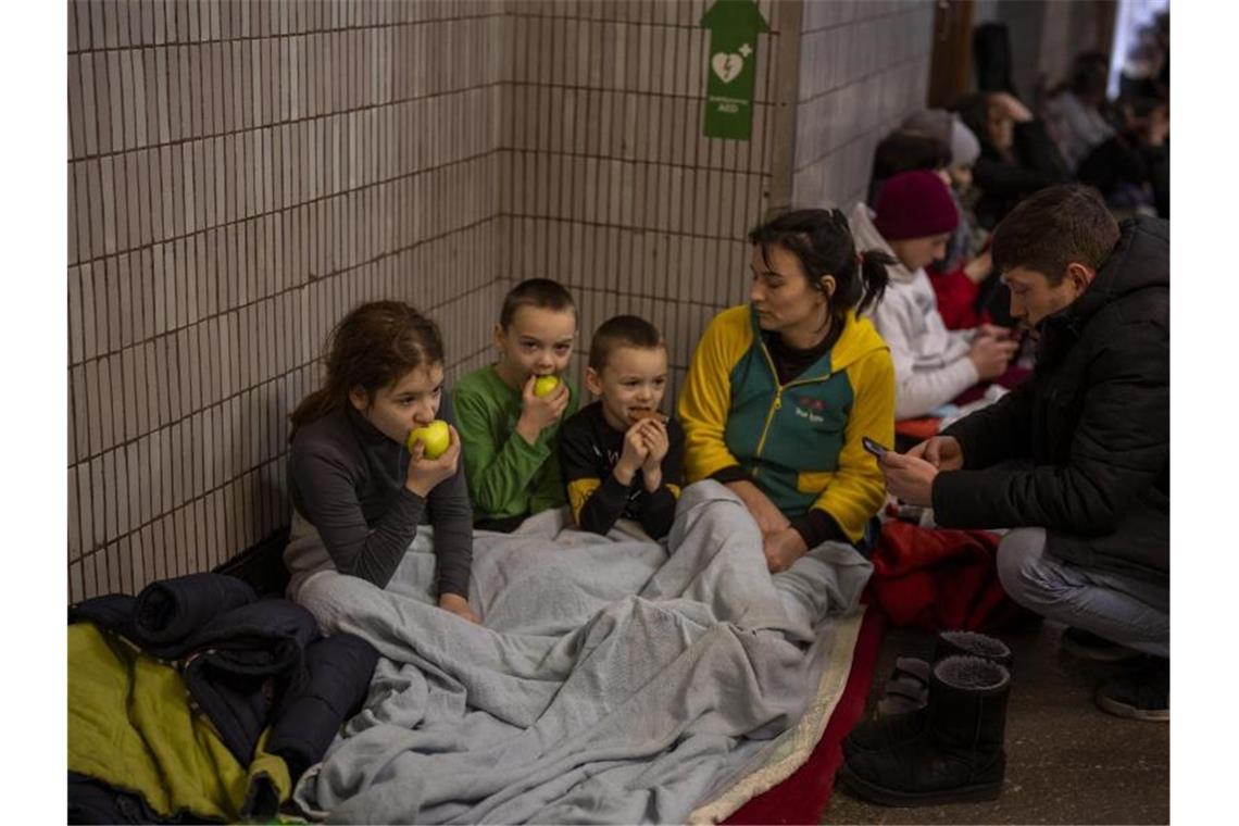 Eine Familie sitzt in einer U-Bahn-Station in Kiew, die als Luftschutzbunker genutzt wird. Foto: Emilio Morenatti/AP/dpa