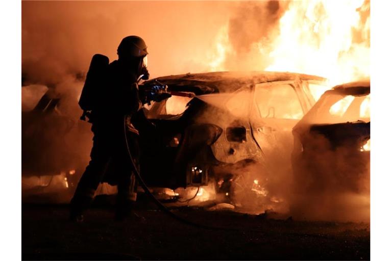 Eine Feuerwehrkraft löscht brennende Autos. Foto: Christian Wiediger/onw-images/dpa