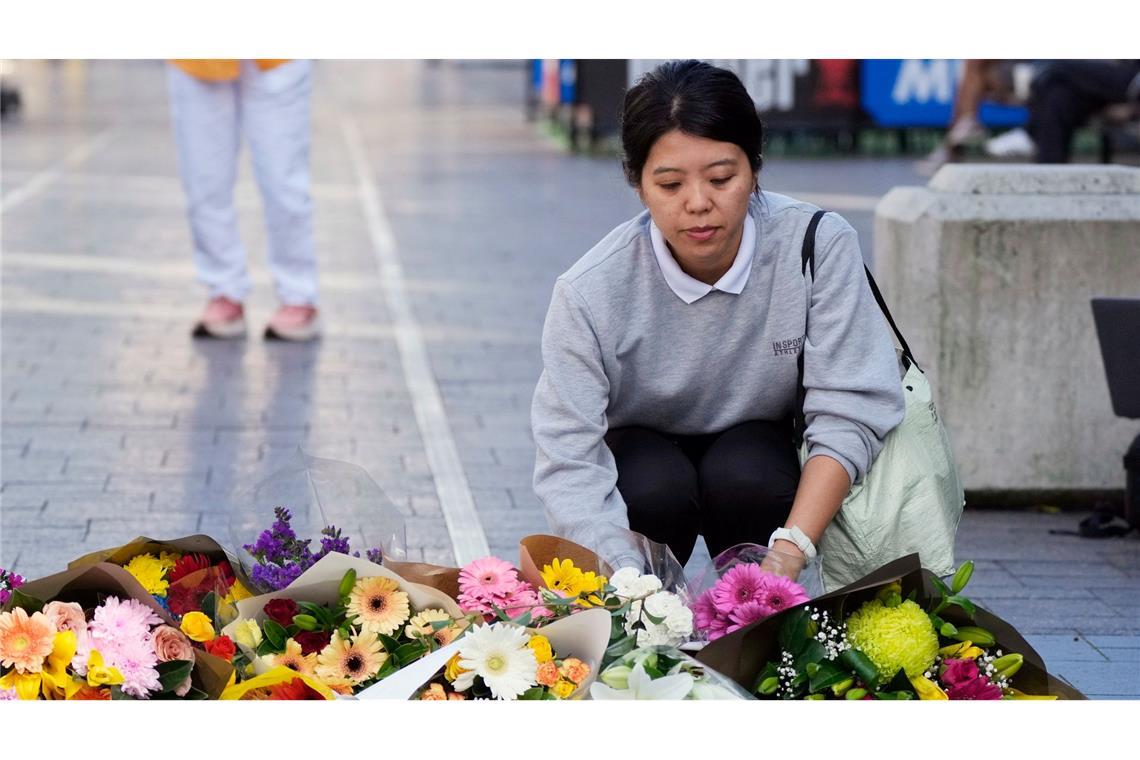 Eine Frau bringt Blumen zu einer improvisierten Gedenkstätte an der Bondi Junction.