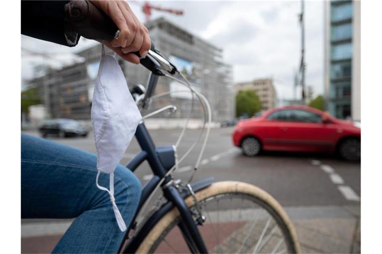 Eine Frau fährt mit Fahrrad und Mundschutz durch Stuttgart. Foto: Sebastian Gollnow/dpa