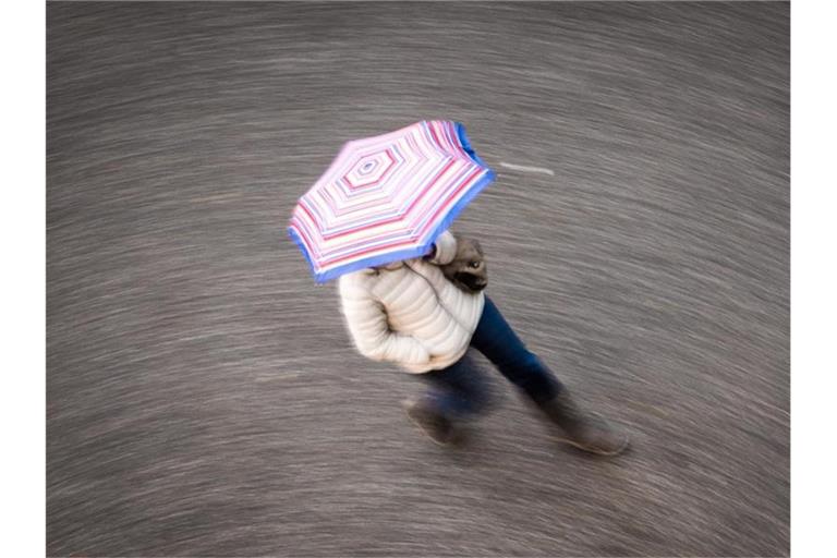 Eine Frau geht bei regnerischem Wetter über eine Straße. Foto: Frank Rumpenhorst/dpa/Symbolbild