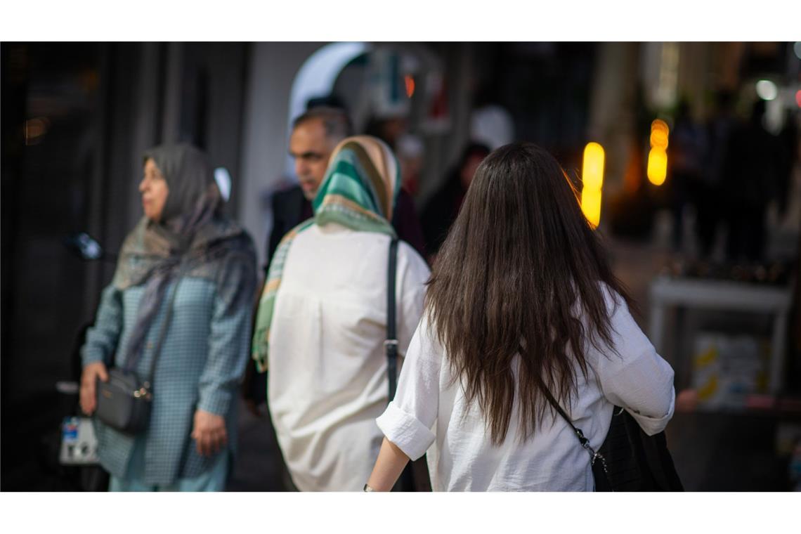 Eine Frau läuft in Teheran mit offenen Haaren eine Straße entlang.