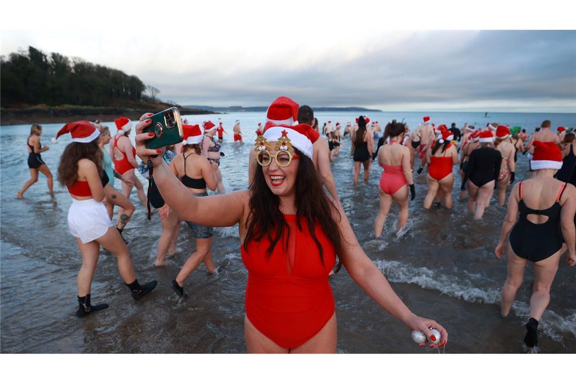 Eine Frau nimmt am jährlichen Weihnachtsschwimmen zu Heiligabend in Helen's Bay in Großbritannien teil und macht ein Selfie.