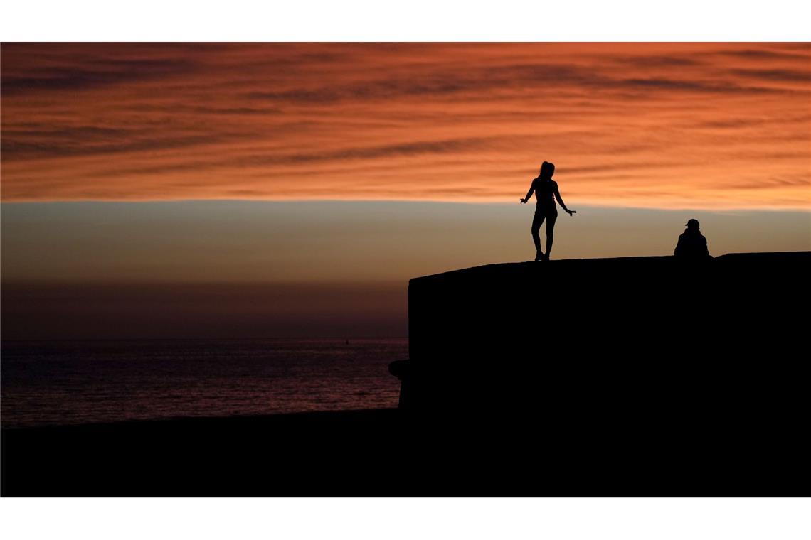 Eine Frau steht an der Uferpromenade von Montevideo in Uruguay vor dem Hintergrund des Sonnenuntergangs.