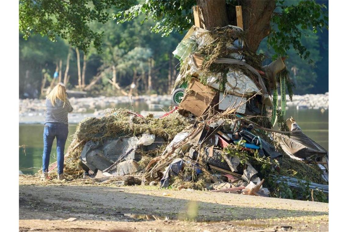 Über 150 Tote nach Hochwassern im Westen Deutschlands Eine Frau steht vor einem Trümmerhaufen in Schuld. Foto: Thomas Frey/dpa