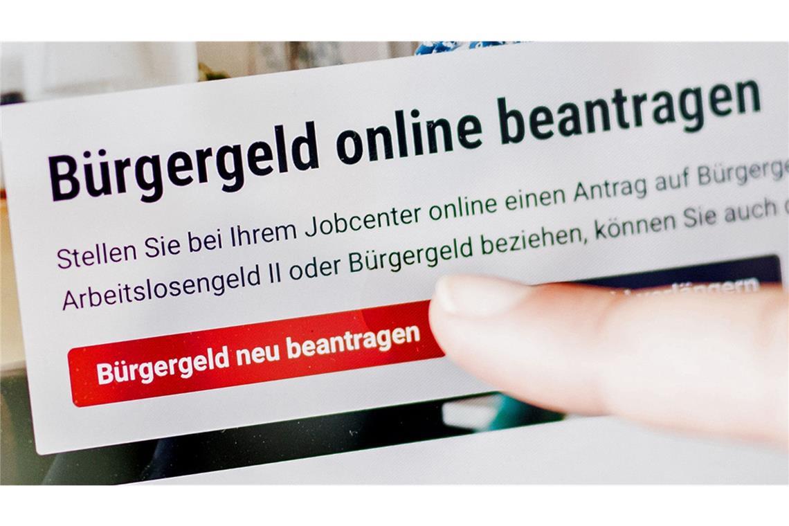 Eine Frau tippt auf einem Tablet auf einen Link zum Beantragen des Bürgergeldes im Kundenbereich im Jobcenter Berlin Mitte.