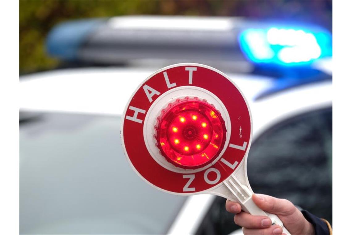 Illegal Auto von der Schweiz nach Deutschland gebracht Eine Haltekelle des Zolls wird vor das Blaulicht eines Einsatzfahrzeuges gehalten. Foto: Sebastian Willnow/dpa-Zentralbild/dpa/Symbolbild
